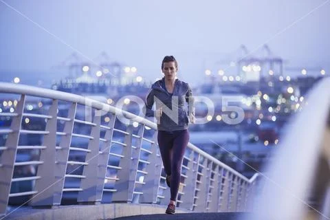 Female runner running on urban footbridge at dawn Stock Photos