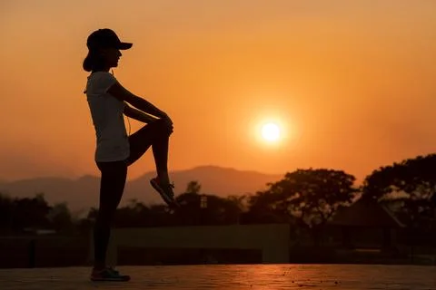 Female runner stretching before run on sunset mountain Stock Photos