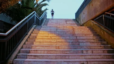 Female runner training up stairs over in urban runway at sunrise Stock Footage 247689217