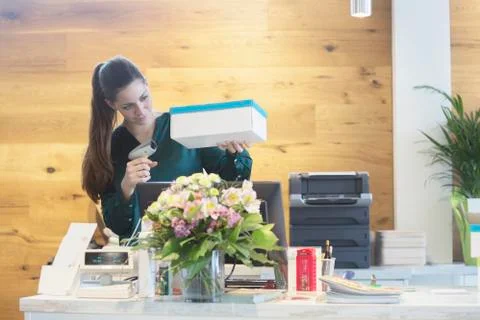 Female sales assistant using barcode reader on shoe box in shoe shop Stock Photos