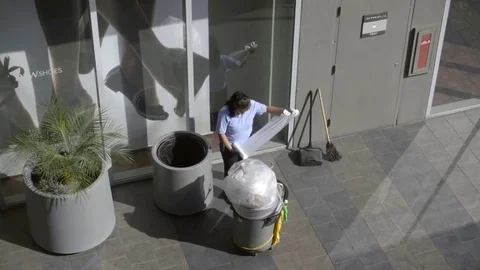 Female sanitation worker changing garbage bag for trash can in outdoor mall LA Stock Footage 70238314