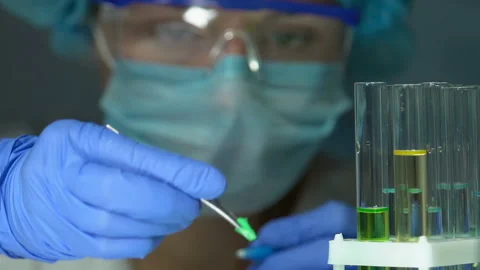 Female scientist adding green reagent into substance in test tube research Stock Footage 104940097