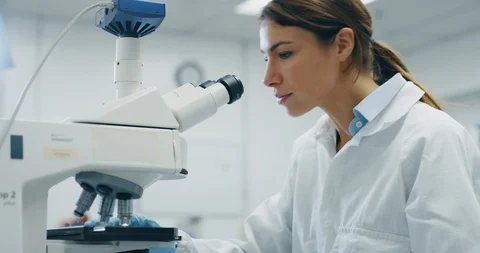 A female scientist analyzes a samples of DNA and molecules with microscope. Stock Footage 115089328