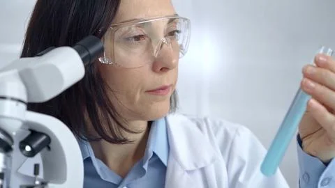 Female scientist analyzing sample of a test tub in laboratory setting. Science Fotos Stock