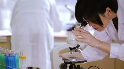 Female scientist bends looks into microscope up medium CU angle Stock Footage 59032658