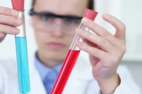 Female scientist comparing test tubes with red and blue fluid substance NTSC Stock Footage 10650827