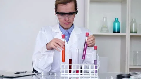 Female scientist comparing test tubes with chemicals and writing results HD Stock Footage 10652283
