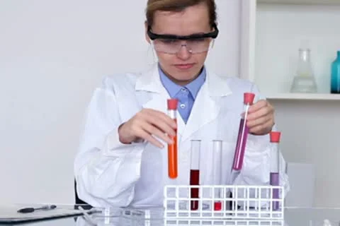 Female scientist comparing test tubes with chemicals and writing results NTSC Stock Footage 10652515