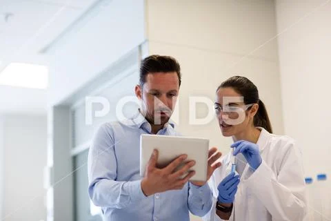 Female scientist discussing results of experiment with male colleague Stock Photos