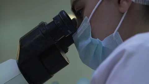 Female scientist examines a sample under a microscope in a laboratory Stock Footage 318463383