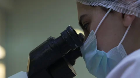 Female scientist examines a sample under a microscope in a laboratory Stock Footage 318463542