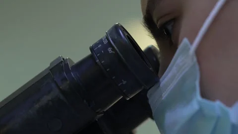 Female scientist examines a sample under a microscope in a laboratory Stock Footage 318463558
