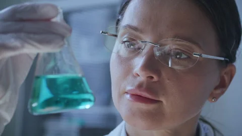 Female Scientist Examining Chemical Solution in Laboratory Flask Stock Footage 337320638