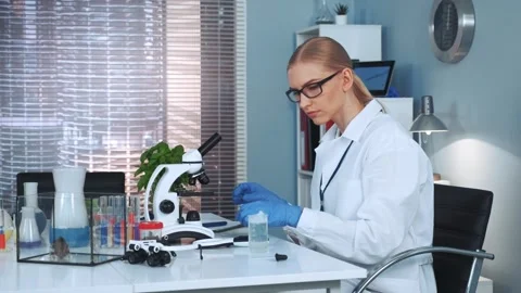 Female scientist examining samples with microscope in research laboratory Stock Footage 340979532