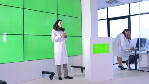 Female scientist explaining in front of green screen display in office Stock Footage 108178078