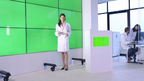 Female scientist explaining in front of green screen display in office Stock Footage 108179304