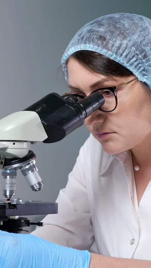 Female scientist in a lab coat and sterile gloves performing research 库存影片 342945451