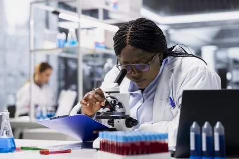 Female scientist in lab examining stained tissue under microscope Stock Photos