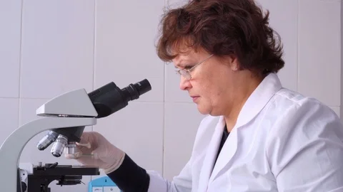 Female scientist looking microscope. Portrait of woman scientist looking through Stock Footage 86080863