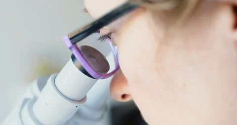 Female scientist looking through microscope Stock Footage 87485174