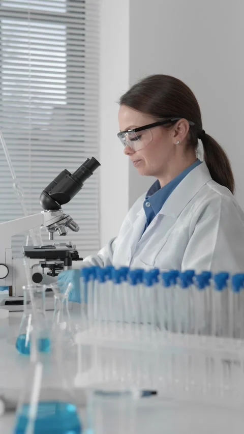 Female scientist in modern laboratory working with microscope and test tubes Stock Footage 340924023