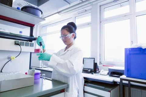 Female scientist pipetting sample into volumetric flask Stock Photos