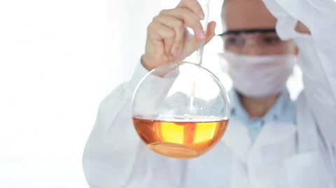 Female scientist pouring red substance from pippete into Volumetric flask HD Stock Footage