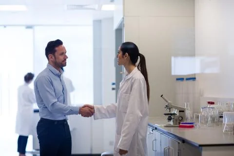 Female scientist shaking hands with pharmaceutical sales rep Stock Photos