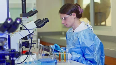 Female scientist using a microscope and tablet to analyze samples Vídeo Stock 346939797