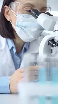 Female scientist using microscope in laboratory. Focus on a woman in lab goggles Stock-Fotos