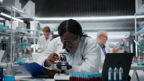 Female scientist using optical microscope to study microorganisms in laboratory Stock Footage 326013211