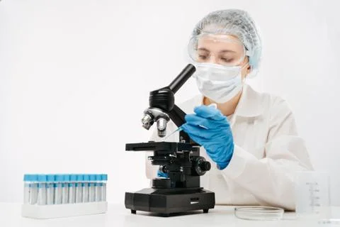 Female scientist working with powerful microscope and reagent in clinic Stock Photos