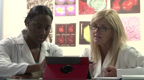 Female Scientists talking and looking at tablet - tilt up Stock Footage 43603330