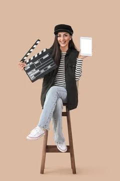 Female scriptwriter with blank tablet computer and movie clapper sitting on b Stock Photos