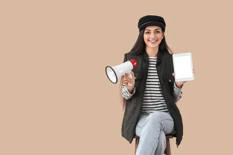 Female scriptwriter with blank tablet computer and megaphone sitting on beige Stock Photos