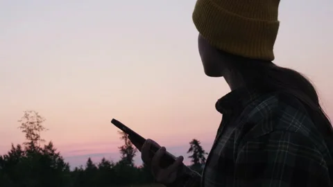Female scroll through applications feed on smartphone during sunset in mountains Stock Footage 200466886