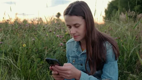 Female scroll through applications feed on smartphone and looking at sunset Stock Footage 201326517