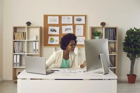 Female secretary working simultaneously on computer and laptop sitting at her Foto stock