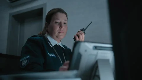 Female security officer or dispatch talks in walkie talkie in monitoring center Stock Footage 281723101