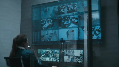 Female security operator watches CCTV cameras using multiple monitors and big Stock Footage 281718600