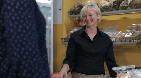 Female seller gets credit card from the client at the pastry shop Stock Footage