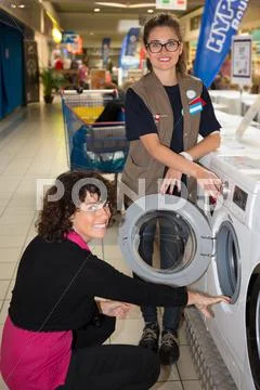 Female Seller helping customer with choosing washing machine Stock Photos