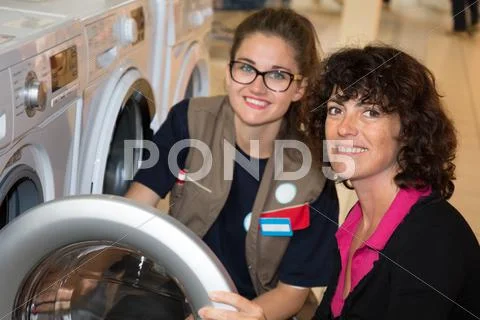 Female Seller helping customer with choosing washing machine Stock Photos
