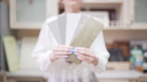 A female seller shows in the camera examples for the choice of furniture Stock Footage 127975481