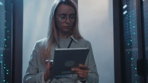 Female server afministrator using digital tablet walking in rack server corridor Stock Footage 119083614