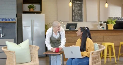 Female server entering cafe with red mug placing beside laptop touching Indian Stock Footage 340069239