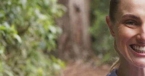 Female shifting into view, making eye contact, grinning on forest trail, copy Stock Footage 336609210