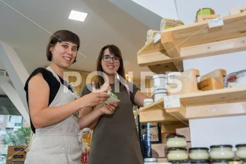 Female shopkeeper helping a customer in zero waste store. Stock Photos