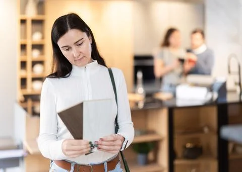 Female shopper carefully selects samples of material for a future kitchen set in Stock Photos