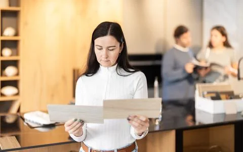 Female shopper carefully selects samples of material for a future kitchen set Stock Photos